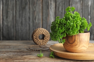 Photo of Bowl with fresh green parsley on wooden table. Space for text