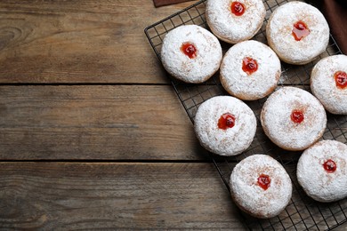 Many delicious donuts with jelly and powdered sugar on wooden table, top view. Space for text
