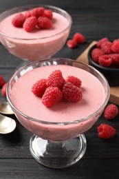 Photo of Delicious raspberry mousse on black wooden table