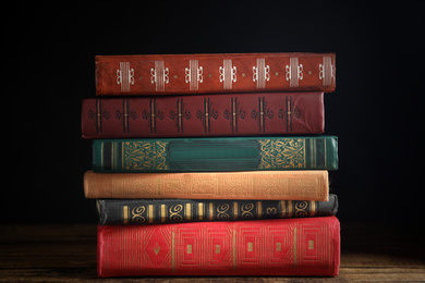 Collection of different books on wooden table against dark background