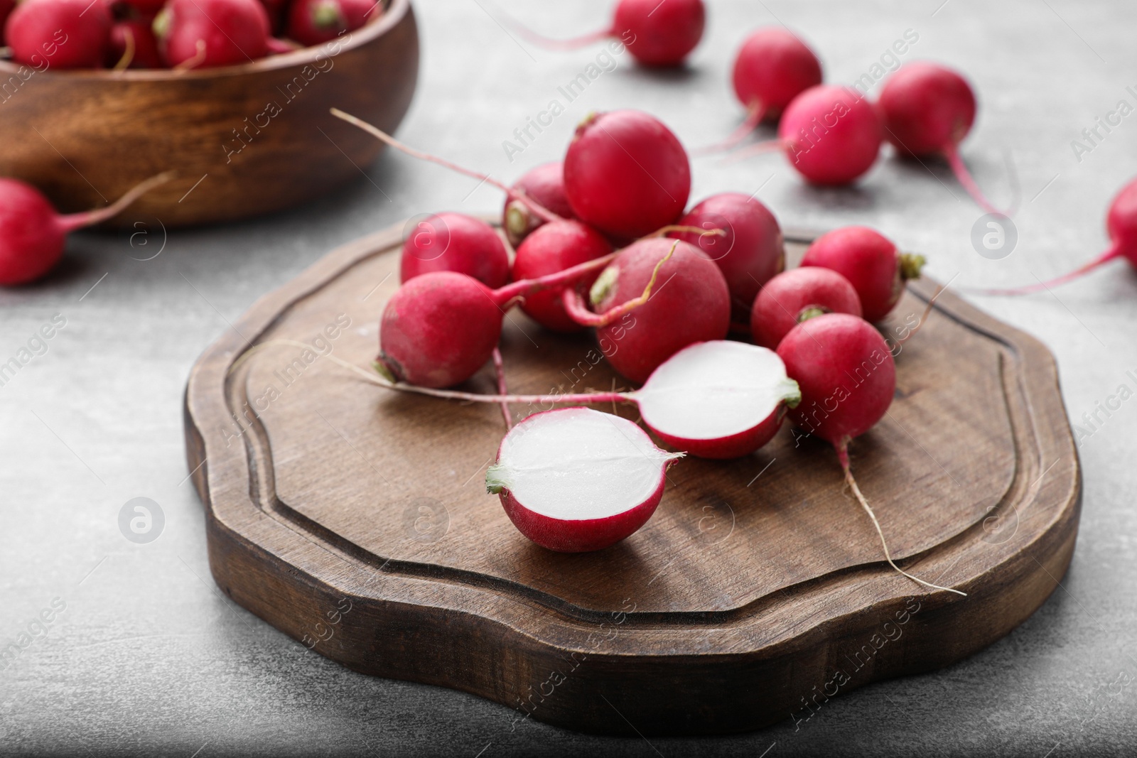 Photo of Wooden board with fresh ripe radishes on grey table