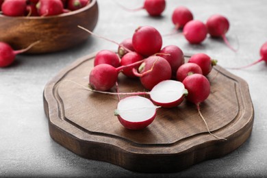 Photo of Wooden board with fresh ripe radishes on grey table