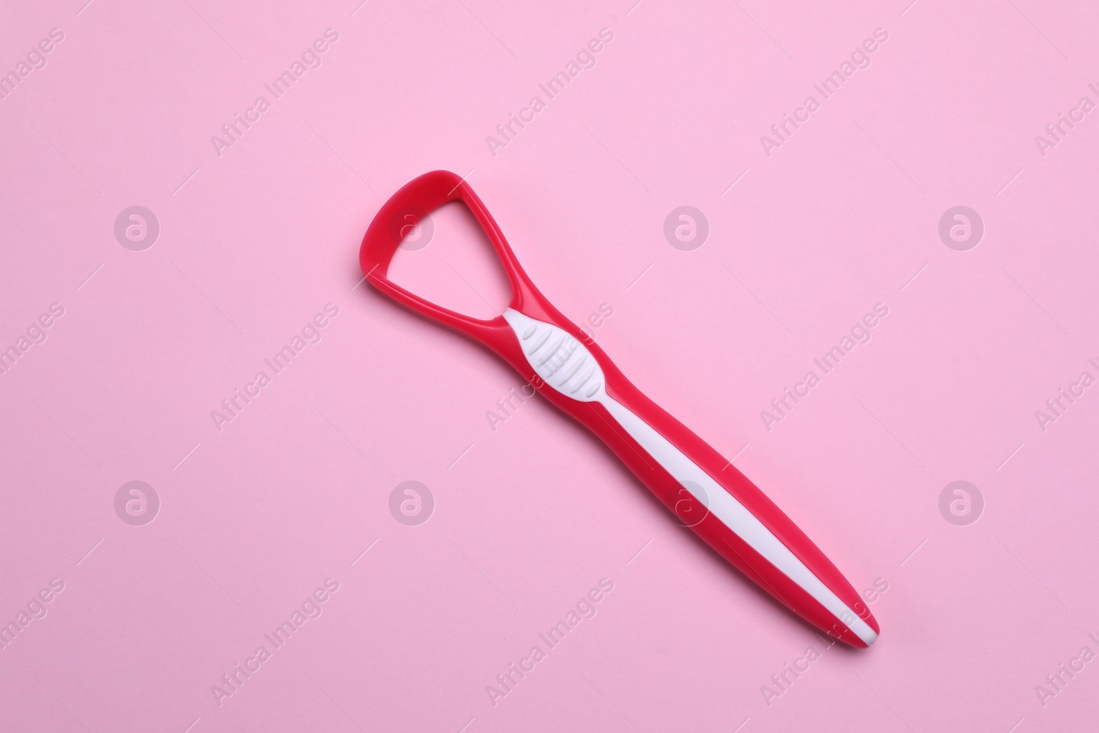 Photo of Red tongue cleaner on pink background, top view