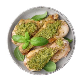 Photo of Delicious fried chicken drumsticks with pesto sauce and basil in bowl isolated on white, top view