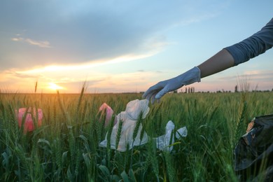 Photo of Woman collecting garbage in wheat field, closeup