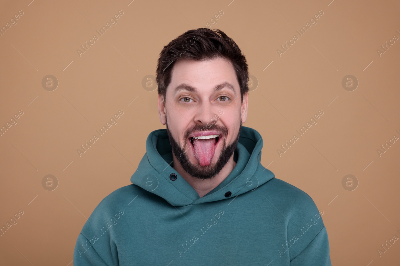 Photo of Happy man showing his tongue on beige background