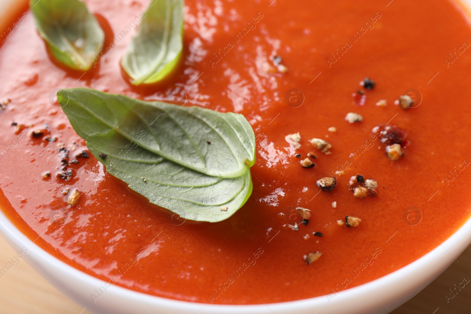 Photo of Delicious tomato soup with basil and spices in bowl, closeup