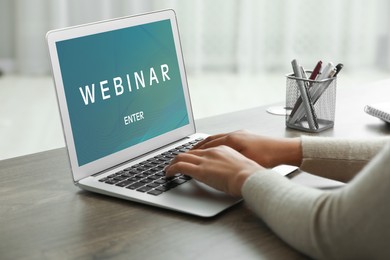 Online webinar, web page on computer screen. Woman using laptop at wooden table, closeup