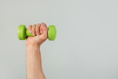 Photo of Man holding dumbbell on grey background, closeup. Space for text
