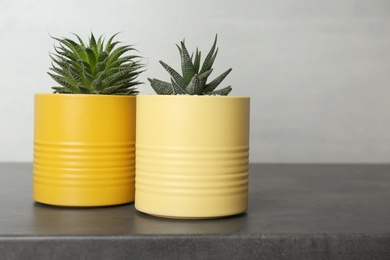 Photo of Houseplants in yellow tin cans on grey stone table