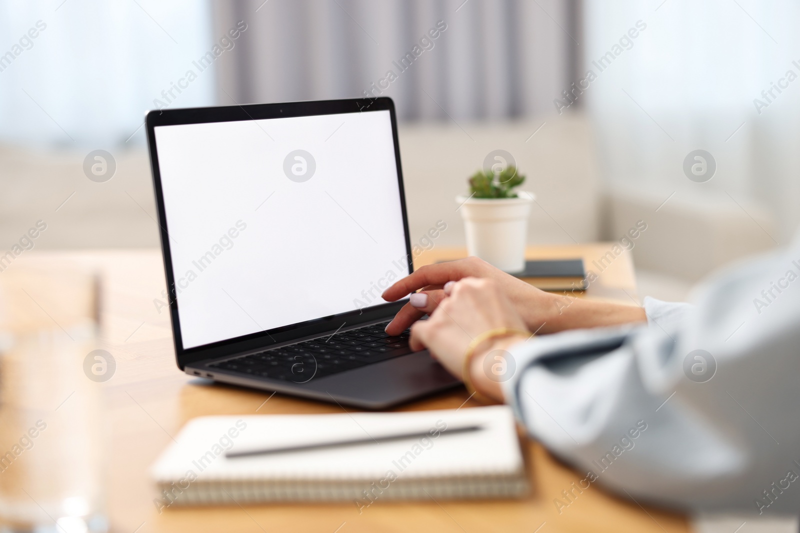 Photo of Young woman watching webinar at table in room, closeup