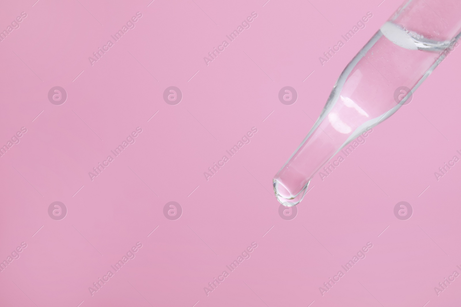 Photo of Dripping serum from pipette on pink background, closeup. Space for text