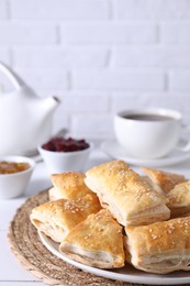 Delicious puff pastry on white table against brick wall