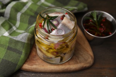 Photo of Tasty marinated fish with onion and rosemary in jar on wooden table, closeup