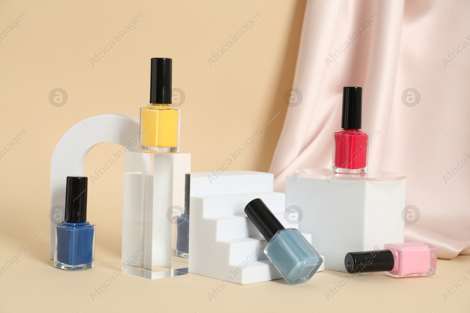 Photo of Stylish presentation of nail polishes on beige background