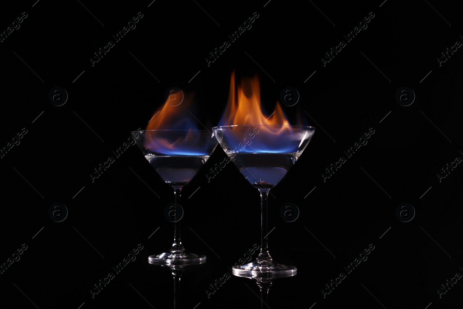 Photo of Cocktail glasses with flaming vodka on black background