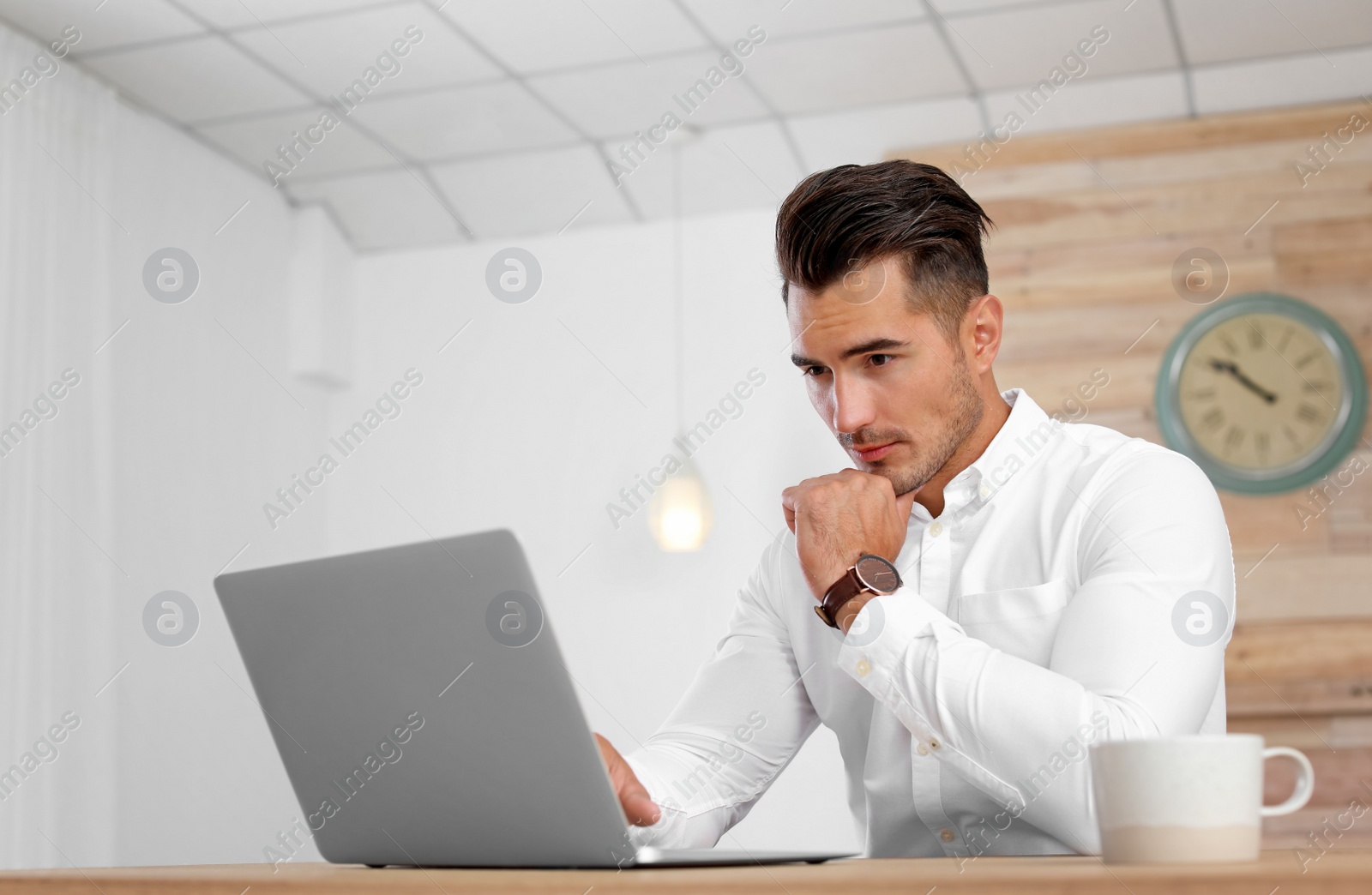 Photo of Portrait of handsome young man with laptop in office
