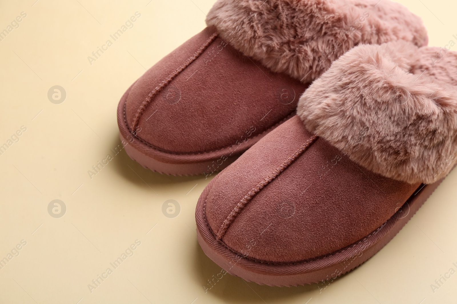 Photo of Pair of stylish soft slippers on beige background, closeup