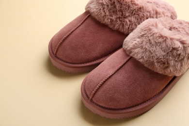 Pair of stylish soft slippers on beige background, closeup