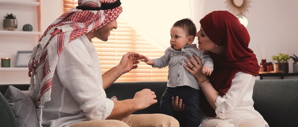 Happy Muslim family with little son in living room. Banner design 