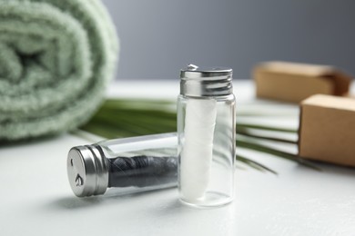 Photo of Biodegradable dental flosses in glass jars on white table