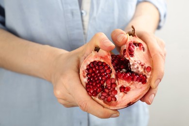 Photo of Woman holding ripe pomegranate on light background, closeup