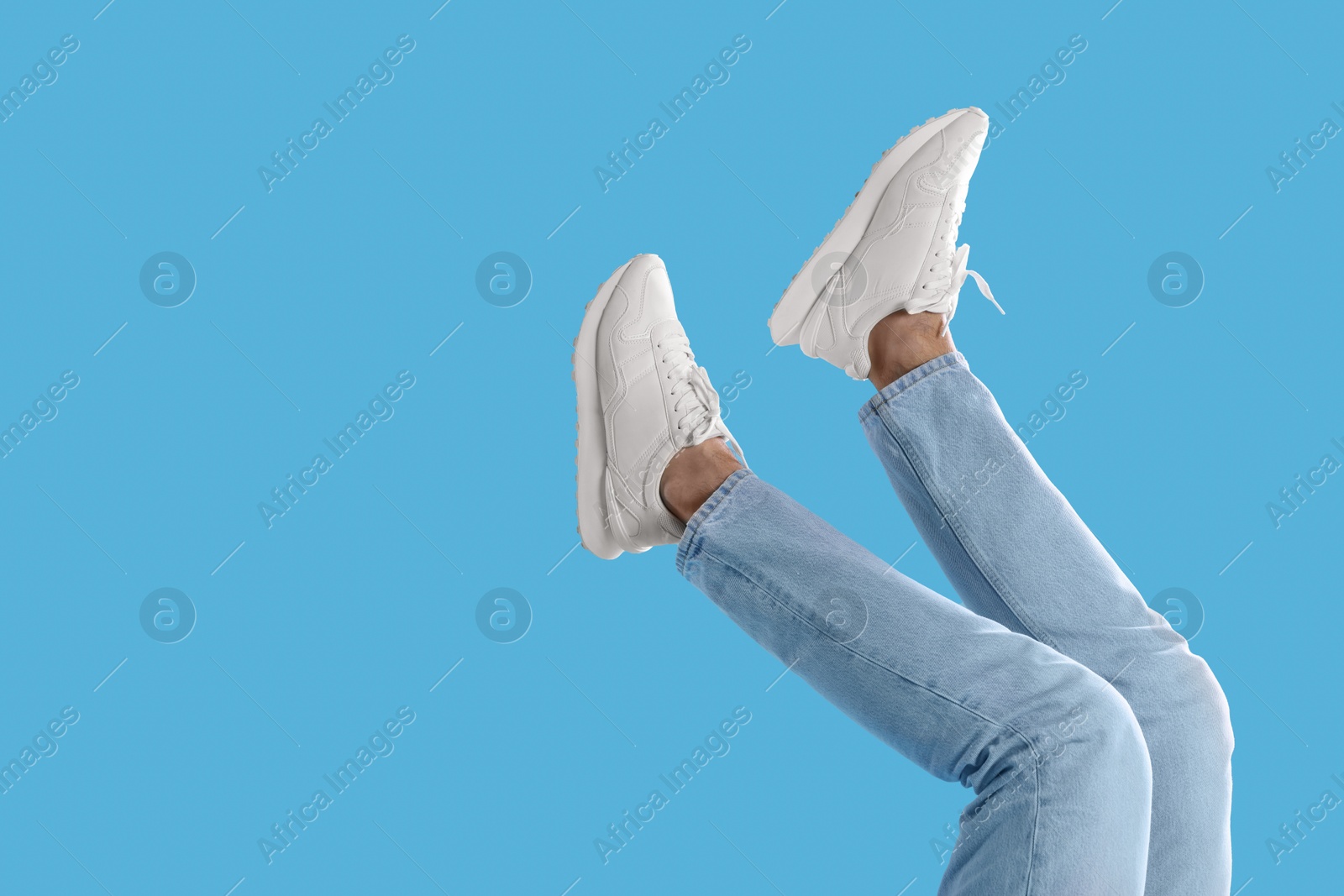 Photo of Man wearing stylish sneakers on light blue background, closeup. Space for text