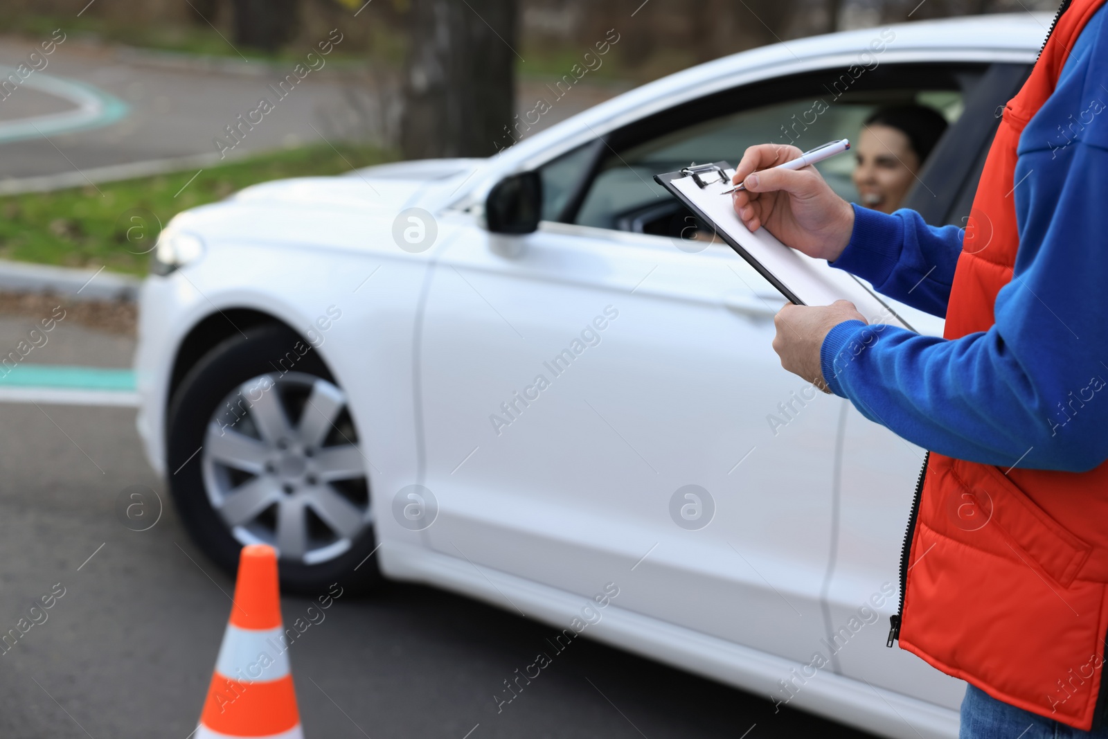 Photo of Instructor with clipboard near car outdoors, closeup. Driving school exam