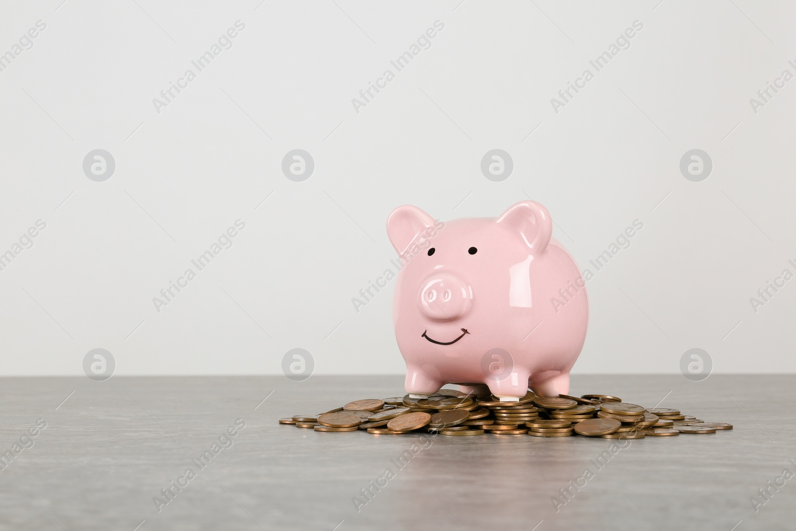 Photo of Piggy bank and coins on table against white background. Space for text