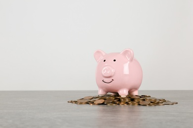 Piggy bank and coins on table against white background. Space for text