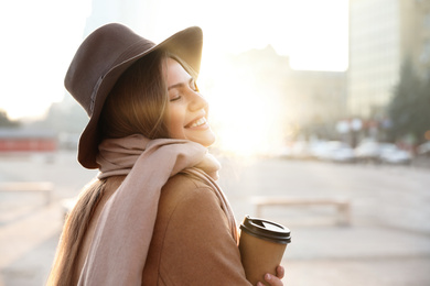 Photo of Young woman with cup of coffee on city street in morning