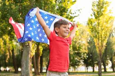 Photo of Cute little boy with American flag in park on sunny day