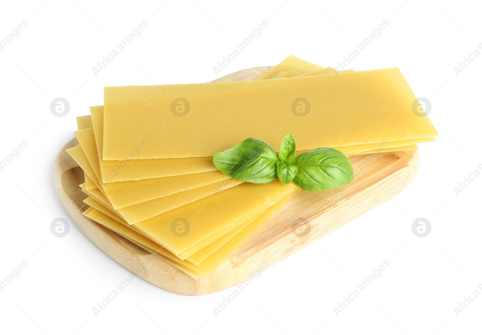 Photo of Wooden board with uncooked lasagna sheets and basil isolated on white