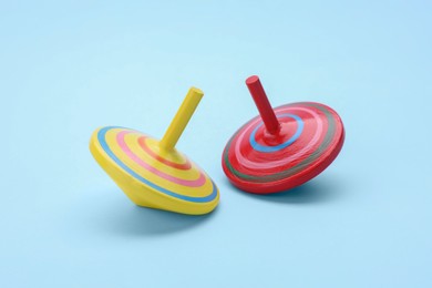 Photo of Two bright spinning tops on light blue background. Toy whirligig