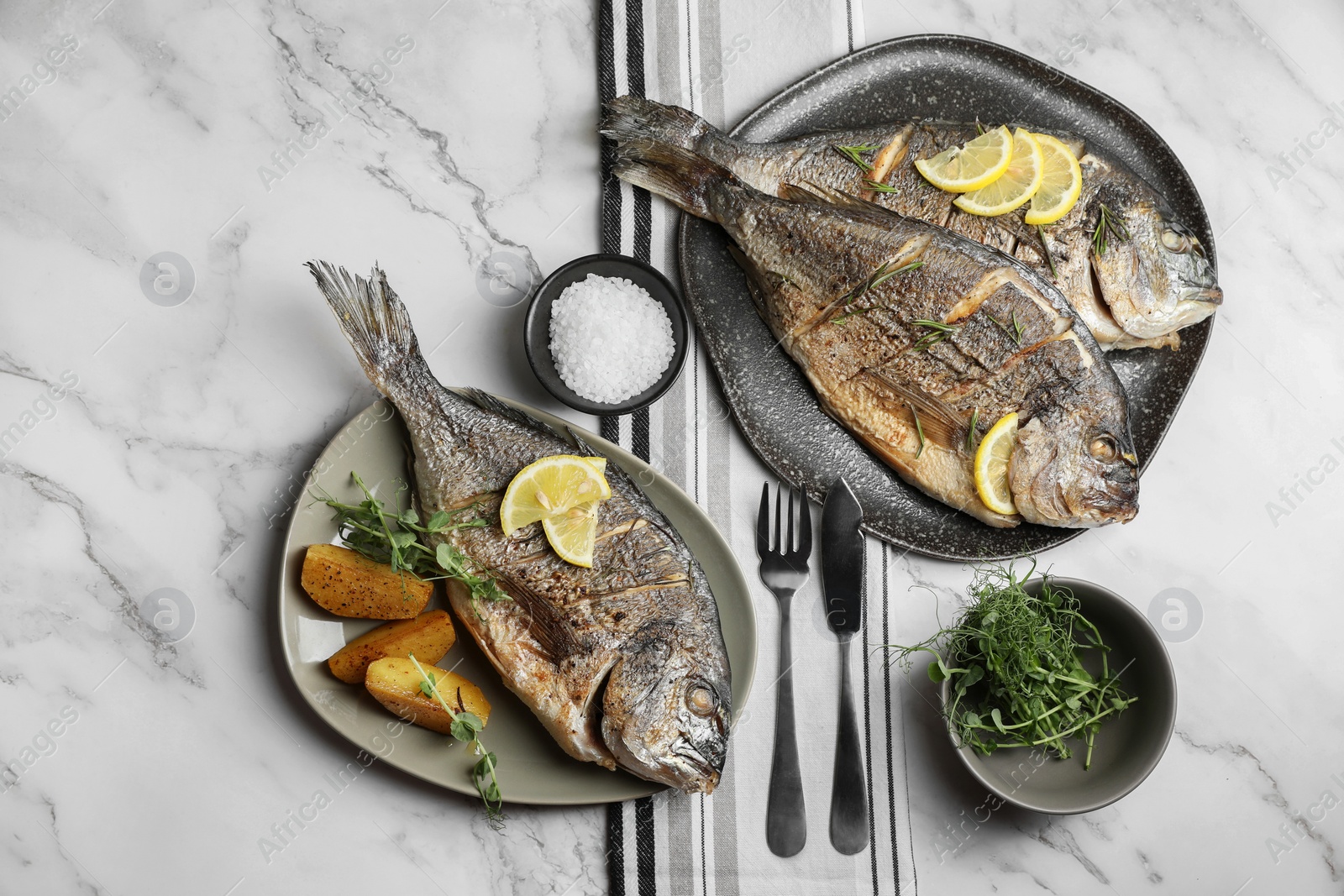 Photo of Seafood. Delicious baked fish served on white marble table, flat lay