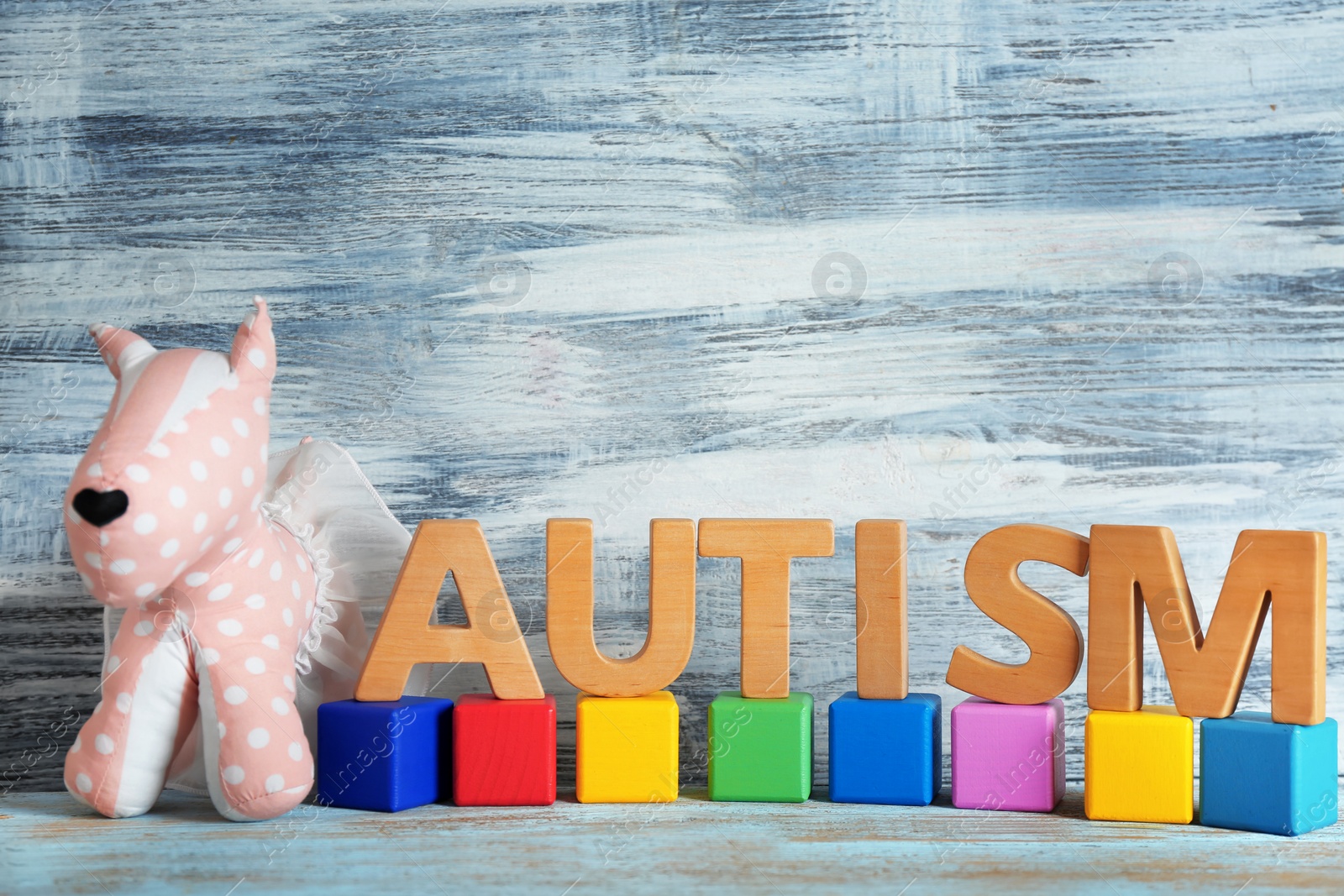 Photo of Word "Autism", toy and wooden cubes on table