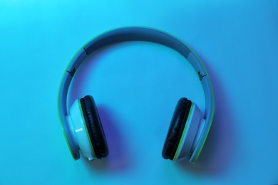 Photo of Stylish modern headphones with earmuffs on color background, top view