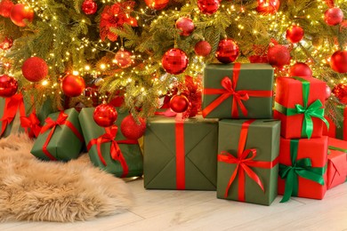 Photo of Many gift boxes under decorated Christmas tree indoors
