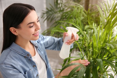 Photo of Woman spraying leaveshouse plants indoors