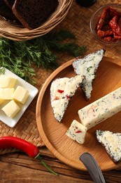 Photo of Tasty butter, dill, chili pepper and rye bread on wooden table, top view