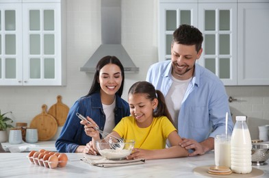 Happy family cooking together at table in kitchen. Adoption concept