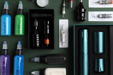 Photo of Flat lay composition with tattoo equipment on dark green background