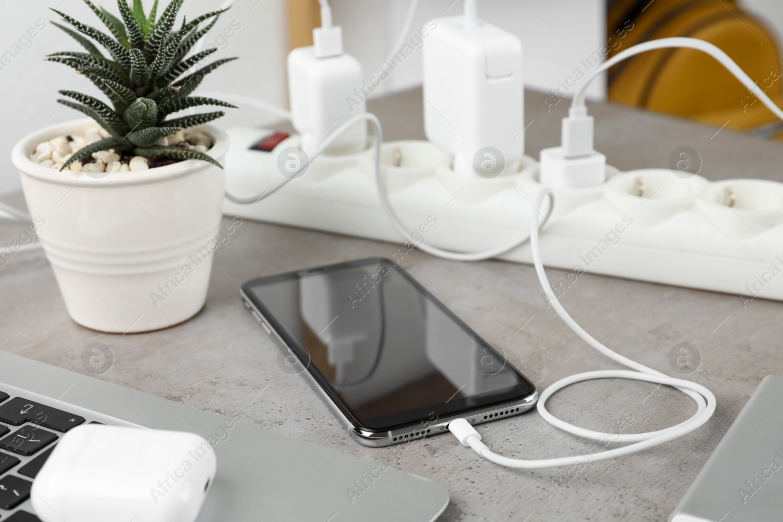 Photo of Smartphone charging with cable on light stone table