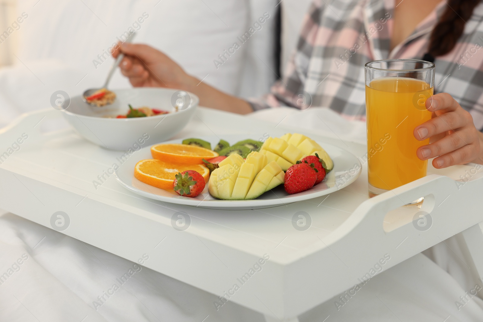 Photo of Young woman having breakfast on bed at home, closeup