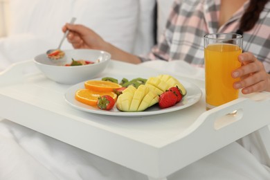 Young woman having breakfast on bed at home, closeup