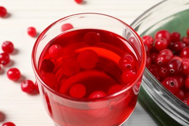 Tasty cranberry juice in glass and fresh berries on white wooden table, closeup