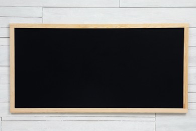 Clean black chalkboard hanging on white wooden wall