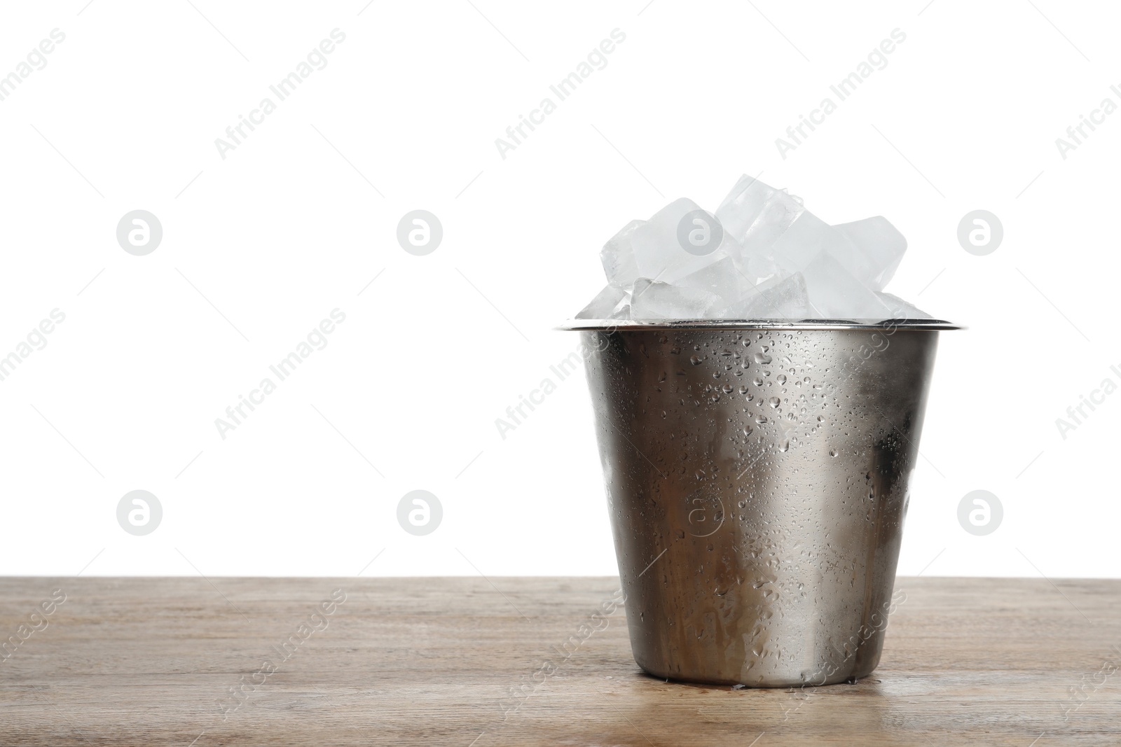 Photo of Metal bucket with ice cubes on wooden table against white background