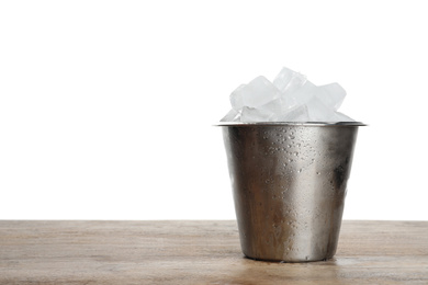 Metal bucket with ice cubes on wooden table against white background