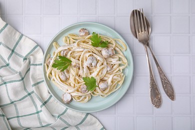 Photo of Delicious pasta with mushrooms served on white tiled table, flat lay